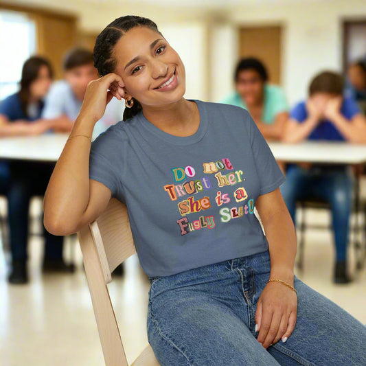 Person wearing a blue t-shirt with colorful text, sitting on a chair against a white background